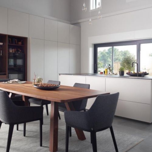 Isla de cocina de color blanco con mesa en color madera y sillas