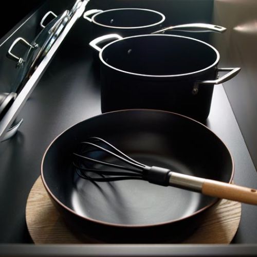 Detalle de utensilios de cocina en tono oscuro guardados en armario